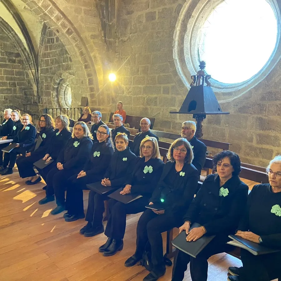 Voces de la coral sentadas en una iglesia con la luz entrando por un rosetón